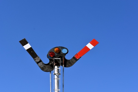 A very old railroad crossing signal system with a background of a clear blue skyの写真素材