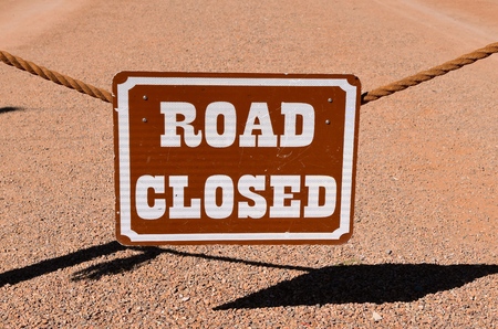 Hanging ROAD CLOSED sign from a rope with shadows cast on the resurfaced roadの写真素材