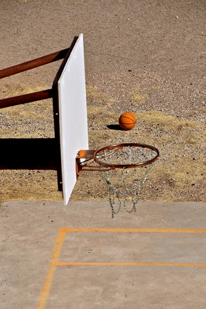 Looking down on an outdoor basketball court with ball, backboard, rim and chain netの写真素材