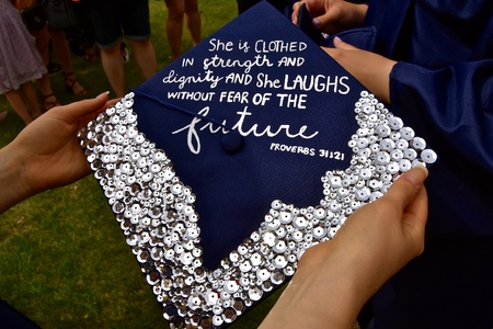 A girl high school student of a private institution holds her graduation cap which is decorated with...