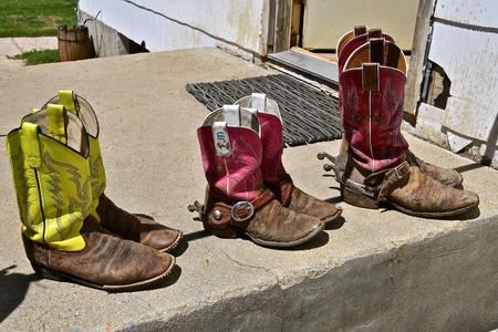 Two adult female and one child female leave weestern boots on the steps to the ranch house.の写真素材