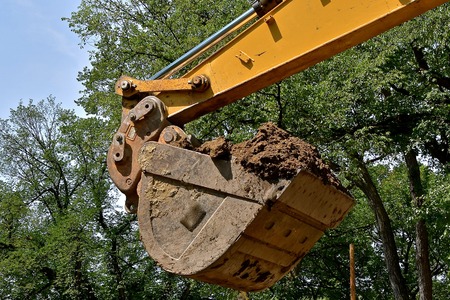 The bucket of a backhoe is filled with clumps of earth at  construction site.の写真素材