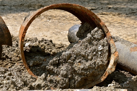 Closeup of rusty and mutilated sewage and sanitary metal pipes dug out in a street repair...