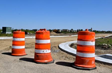 Orange barrels in a construction zone prevents traffic through a new roadway which only has curbs and gutters in place.の写真素材