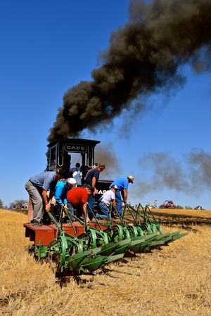 ROLLAG, MINNESOTA, September 1, 2018: Unidentified volunteers ride a gang plow pulled by a steam engine in field demonstrations at the annual WCSTR farm threshers reunion in Rollag held each labor Day weekend where thousands attend.のeditorial素材