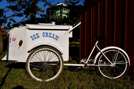 An old three wheeled  pedal bike has been converted into a a mobile ice cream shop