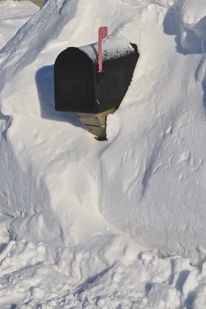 A mailbox nearly  buried in a snowdrift required digging to receive the daily mail after a snowstorm.の写真素材