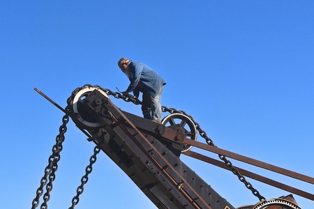 ROLLAG, MINNESOTA, September 2, 2018: A machinist greases the chains of an old excavating drag line...