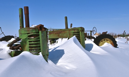 BARNESVILLE, MINNESOTA, March 11, 2019: The old John Deere tractor partially buried by snow was made from John Deere Co, an American corporation that manufactures agricultural, construction, forestry machinery, diesel engines, and drivetrainsのeditorial素材