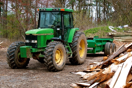 ROWLEY, MASSACHUSETTS, April 28, 2019: The  7400 John Deere tractor  pulling a trailer at a sawmill is a product of John Deere Co, an American corporation that manufactures agricultural and construction equipment, drive trains, and transmissionのeditorial素材