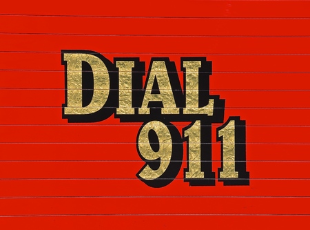 A red Dial 911 sign is on the side of a fired and rescue vehicle