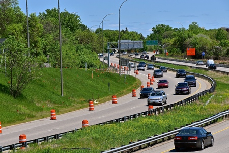A four lane highway with one way traffic displays orange barrels indicating road constructionの写真素材