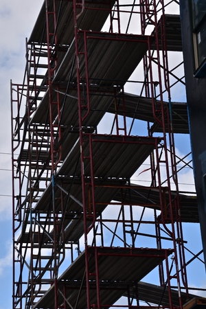 Levels of scaffolding are silhouetted against the sky on the remodeling of a huge buildingの写真素材