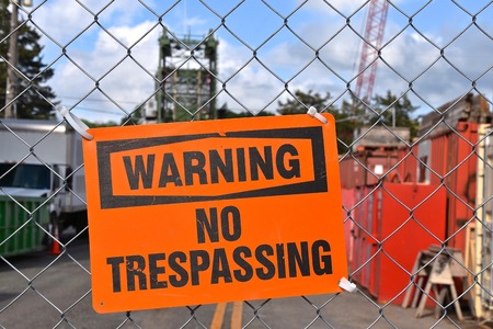 A `Warning No Trespassing` sign is posted on a gate of a construction site.の写真素材