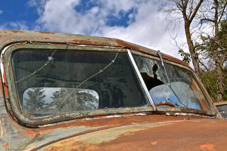 An old rusty pickup is full of patina and has a broken front windshieldの写真素材
