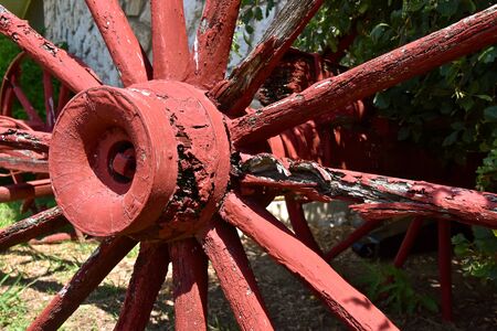 The hub and spokes of an old wooden wagon or cart wheel shows signs of wear and deterioration.の写真素材