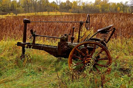 The skeleton frame of an old tractor is surrounded by the colors of autumnの写真素材