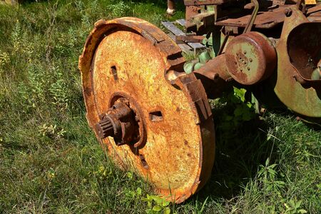 The rusty wheel without a tire belongs to an old tractor.の写真素材