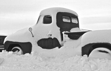 Side profile of an old pickup buried in snow after a blizzard (black and white)の写真素材