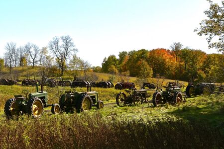 VERGAS, MINNESOTA, October 6, 2019: A row of very old John Deere tractors lined up in a pasture are products of John Deere Co, an American corporation that manufactures agricultural and construction equipment, drive trains, and transmissionのeditorial素材