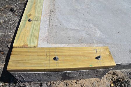 A foundation for a newly poured slab for a garage has sill plate or sole plate placed on the corner...