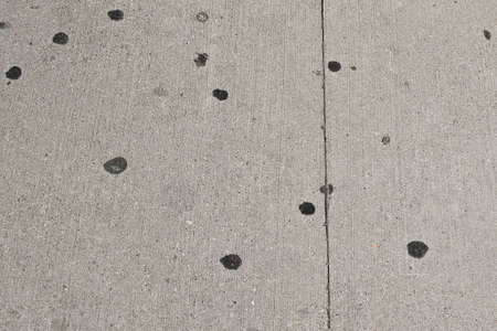 Wads of gums imprinted upon the sidewalk make black circles.の写真素材