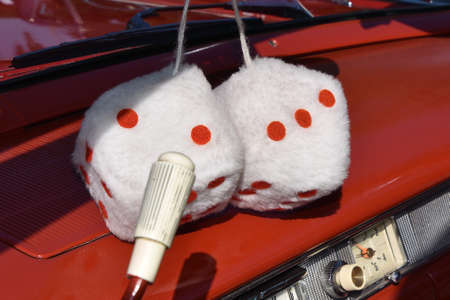 A pair of dice hang from the mirror on the interior of a classic old car of the 50's