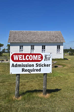DE SMET, SOUTH DAKOTA, August 5, 2020: The admission sticker sign and schoolhouse building are found on the Laura Ingalls Wilder grounds where the family moved in 1879のeditorial素材