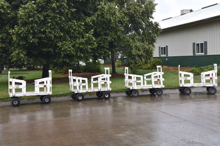 Mini hayracks used as people movers are parked during rain at a fairgrounds festival.