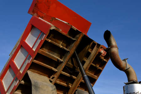 A tandem commercial dump truck for transporting heavy load  exposes the bottom of the box and...