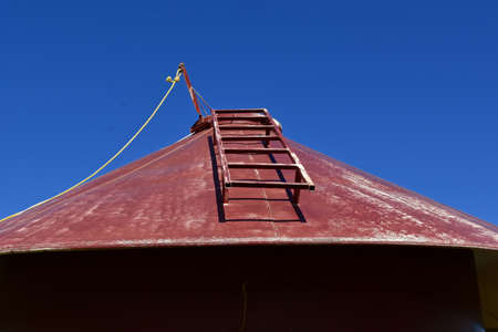 The roof and ladder of an old portable round metal feed bin for cattierの写真素材