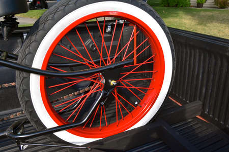A beautiful painted and restored rear wheel and tire of a vintage motorcycle.