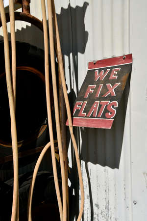 Old advertising sign WE FIX FLATS alongside a hanging air hoseの写真素材