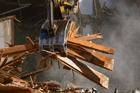 The jaws of of an excavating machine move a load of refuse from a demolition project of an old commercial building.の写真素材