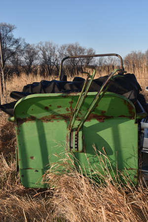 An old green manure spreader is loaded with huge tractor tiresの写真素材