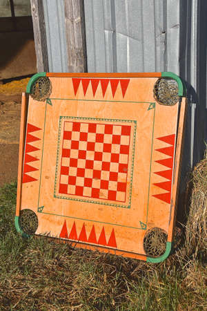 An old  wooden carom board  with the four corner pockets leans against a metal shedの写真素材