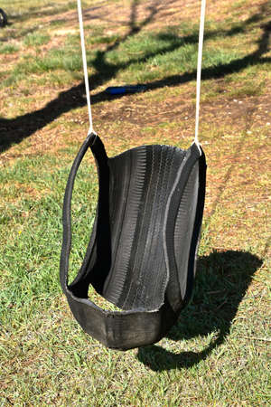 An old tire has been cut to make a comfortable seat and hangs from a tree branchの写真素材