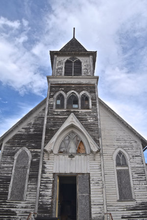 An old neglected white country church is in the first stages of disrepair.
