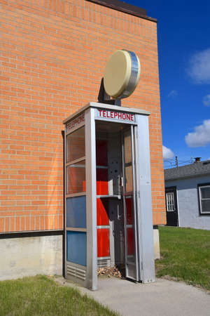 A retro telephone booth with an open door lacking the pay phoneの写真素材