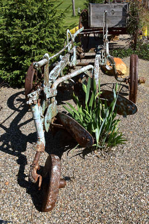 An old two bottom steel plow serves as a backyard decorationの写真素材