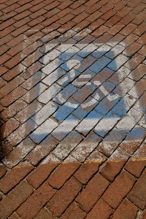 A faded handicapped parking space is painted on a cobblestone road.の写真素材