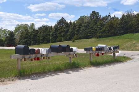 A series of various styles and colors of mailboxes line up on a rural roadの写真素材