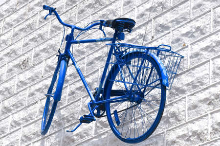 An entirely  retro blue bike hangs suspended against a metal fake block wall.の写真素材