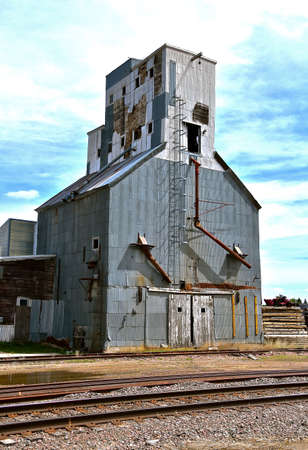 An old neglected grain elevator adjacent to unused railroad tracks reflect memories of yesterdayの写真素材