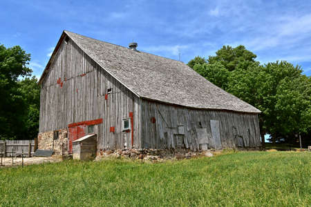 A beautiful weathered horse barn with a hay loft rests on a rock poured foundation.の写真素材