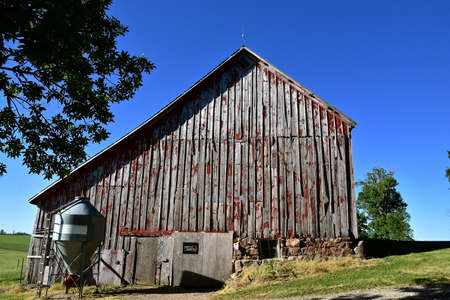 A beautiful weathered horse barn with a hay loft rests on a rock poured foundation.の写真素材