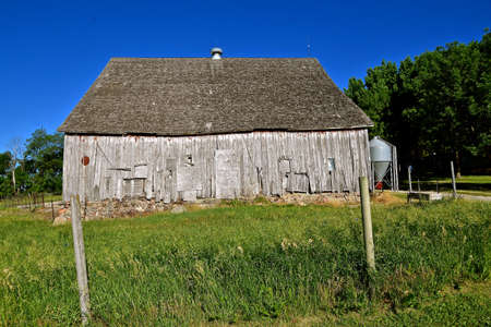 A beautiful weathered horse barn (side profile) with a hay loft rests on a rock poured foundation.の写真素材