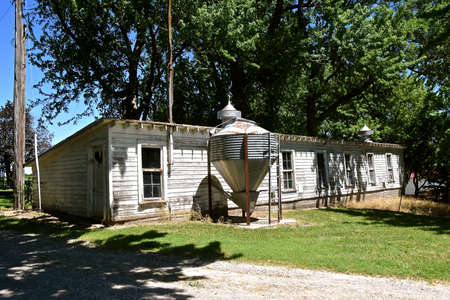 Front of a long old weathered chicken house with a feed tank.の写真素材