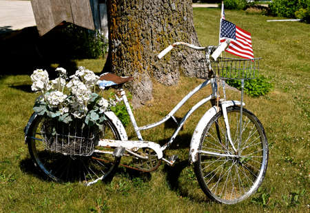 An old white girls bike is decorated with a basket of flowers and an American flag.の写真素材
