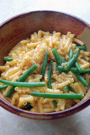 Ceramic bowl of macaroni and cheese with green beans and fresh cracked pepperの写真素材